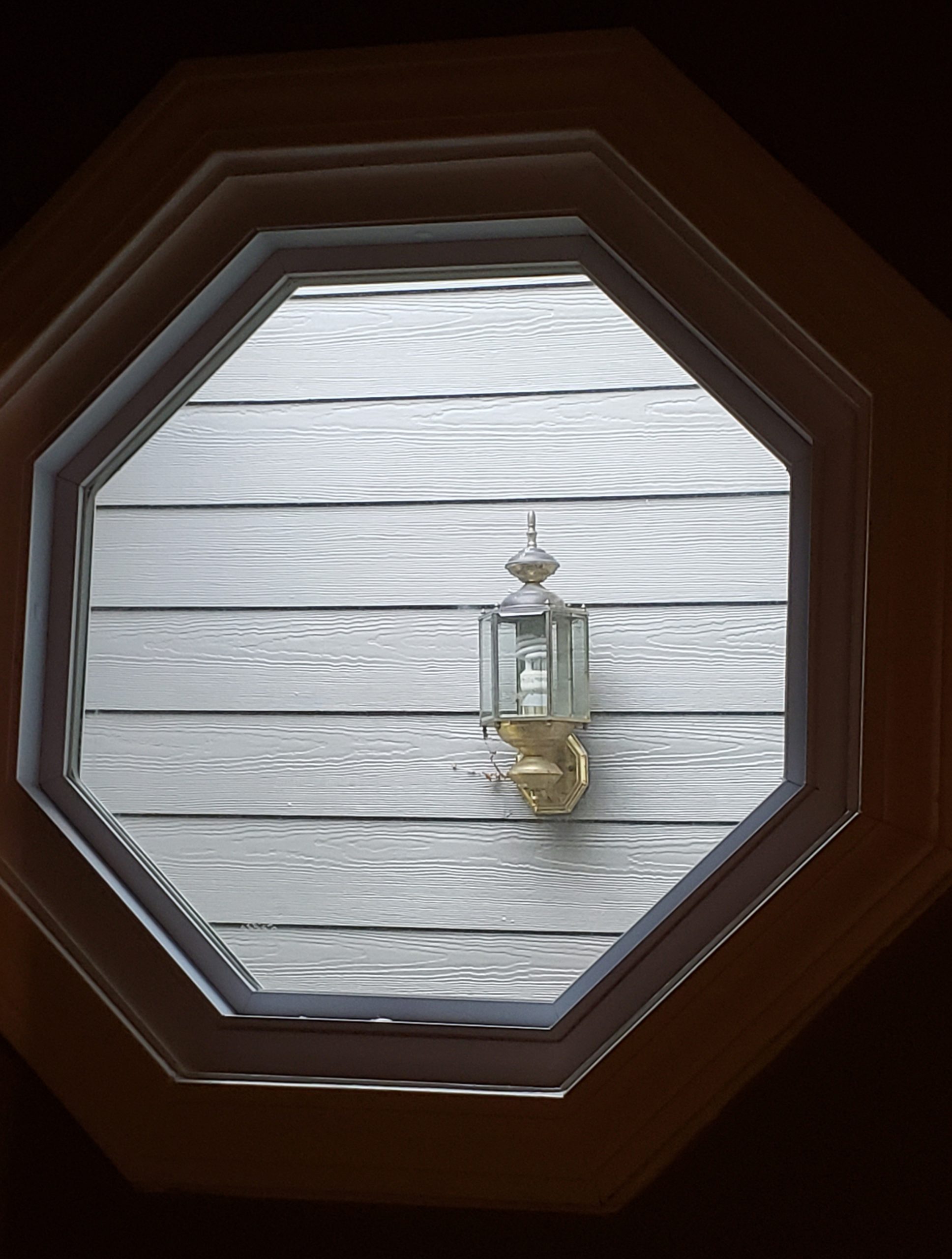 Before: An old and tired outdoor light as seen through an octagonal window. - Lighting Makeover: Our Lights in a Real Home (My Home!) - LightsOnline.com Blog